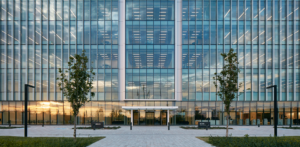 The front of a building reveals rows upon rows of the Rail luminaire on multiple levels behind the reflection of a sunset on the windows.